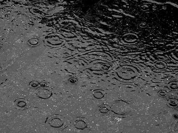 a monochrome picture of raining falling onto pavement